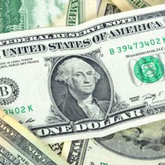 Dólar hoje em queda. Imagem de uma nota de 5 dólares com a bandeira dos EUA, ilustrando a baixa da moeda americana em relação ao real, influenciada pela expectativa de corte de juros pelo Fed.