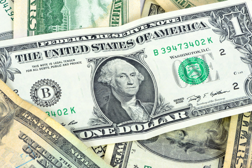 Dólar hoje em queda. Imagem de uma nota de 5 dólares com a bandeira dos EUA, ilustrando a baixa da moeda americana em relação ao real, influenciada pela expectativa de corte de juros pelo Fed.