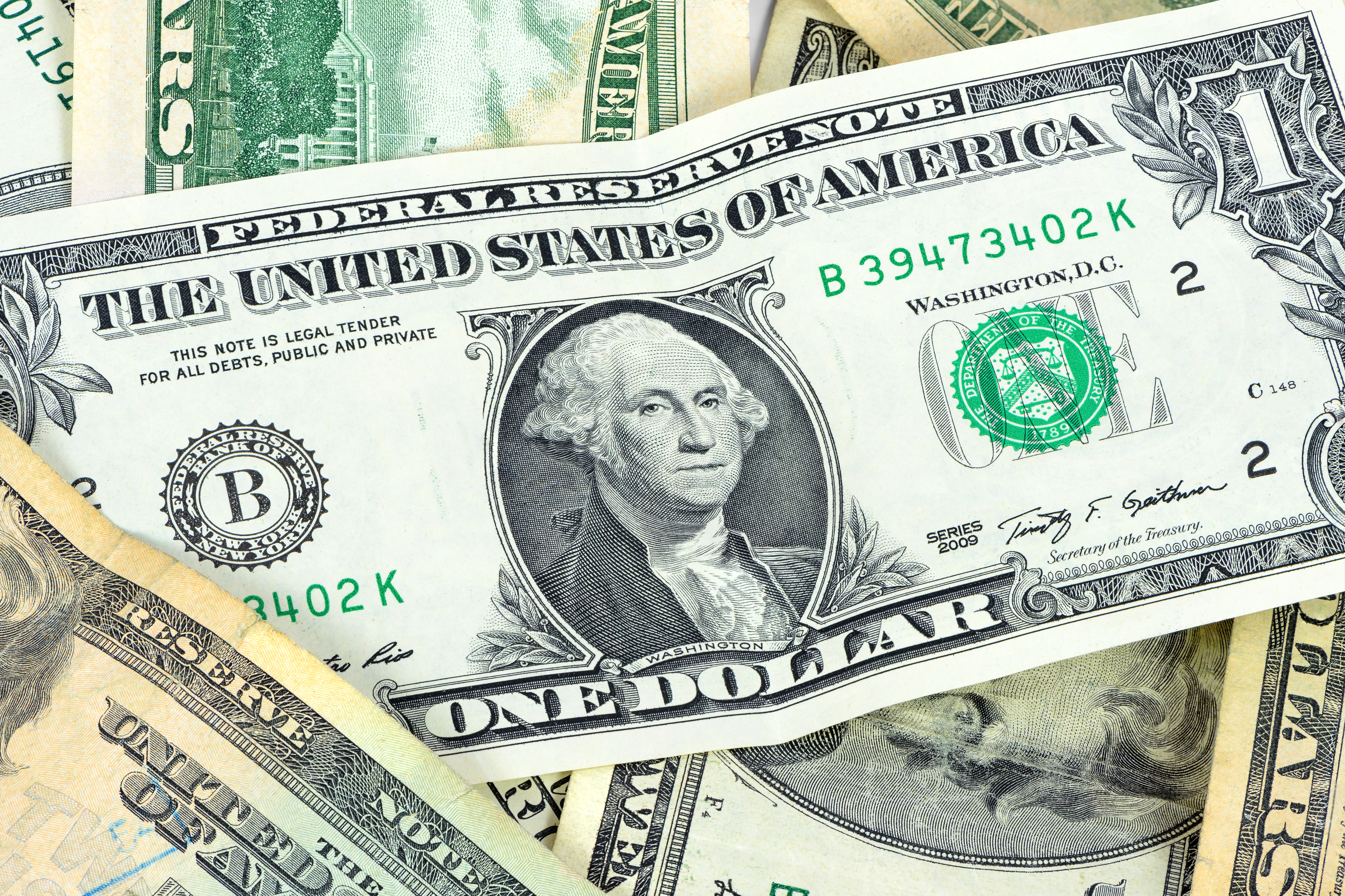 Dólar hoje em queda. Imagem de uma nota de 5 dólares com a bandeira dos EUA, ilustrando a baixa da moeda americana em relação ao real, influenciada pela expectativa de corte de juros pelo Fed.