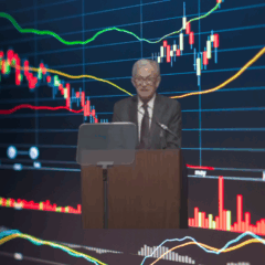 Gráfico financeiro ao fundo com Jerome Powell em discurso sobre política monetária nos EUA.