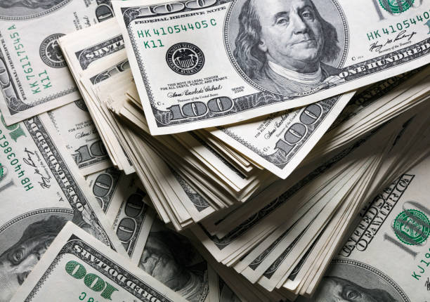 Pilha de notas de 100 dólares americanos empilhadas, destacando riqueza e finanças.