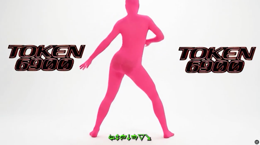 Pessoa em traje rosa neon dançando em fundo branco, com o texto “TOKEN 6900” em destaque, representando um meme visual ligado a criptomoedas.