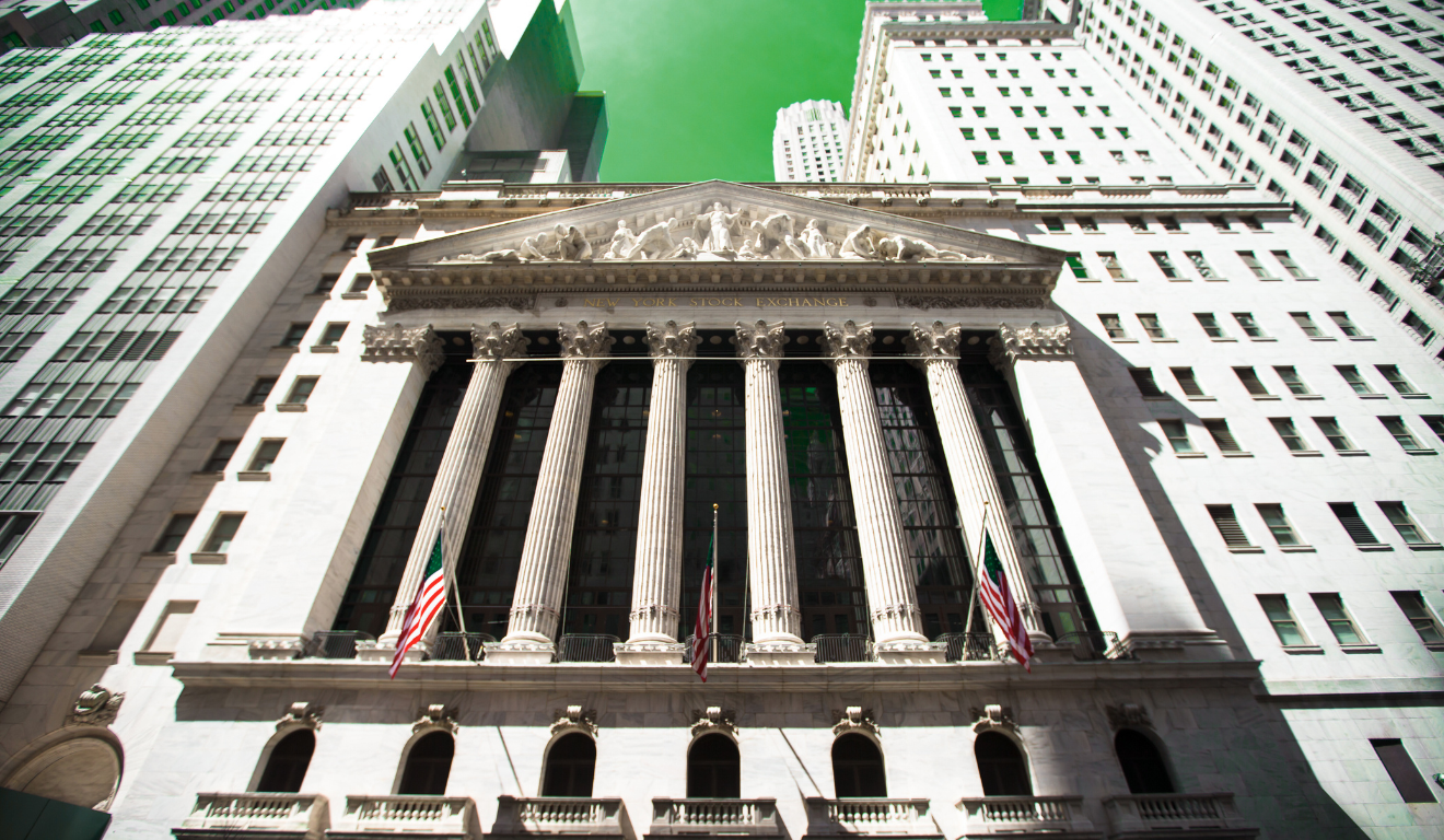 Fachada de Wall Street com bandeira dos EUA representando Bolsas de NY em recorde.