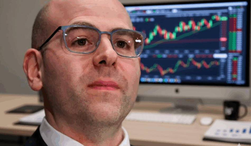 Stephen Miran, diretor do Federal Reserve, com gráficos de mercado ao fundo, discutindo política de juros.