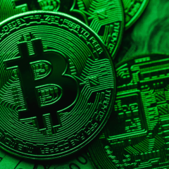 Moeda física de bitcoin iluminada em verde, indicando recuperação do mercado.