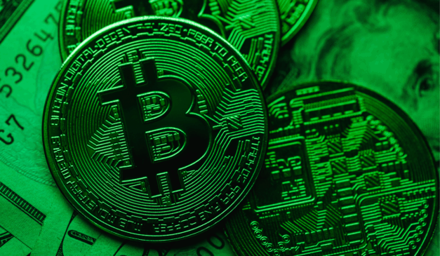Moeda física de bitcoin iluminada em verde, indicando recuperação do mercado.
