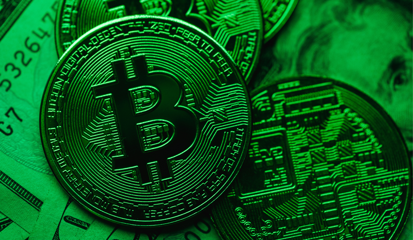Moeda física de bitcoin iluminada em verde, indicando recuperação do mercado.