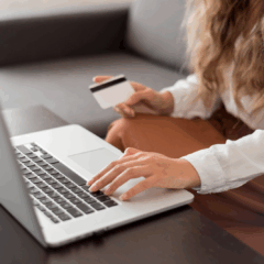 Mulher usando notebook e segurando cartão de crédito enquanto faz compras online