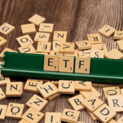 Peças de Scrabble formando a sigla ETF em suporte verde, representando fundos de índice.