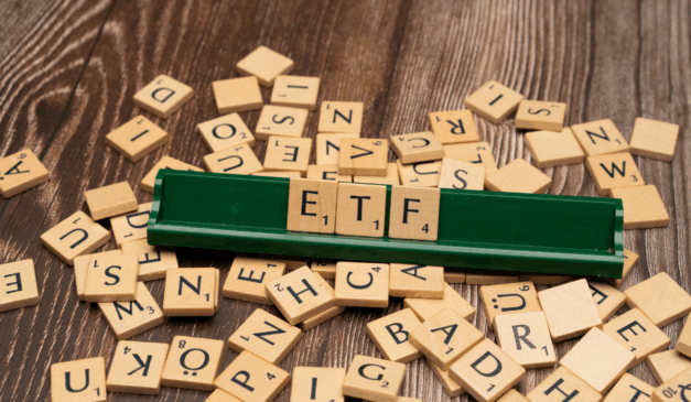 Peças de Scrabble formando a sigla ETF em suporte verde, representando fundos de índice.