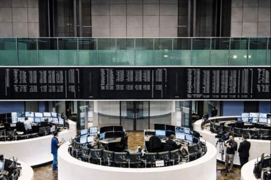 Salão de negociações de bolsa europeia com operadores diante de telas e painéis eletrônicos durante sessão de queda do mercado