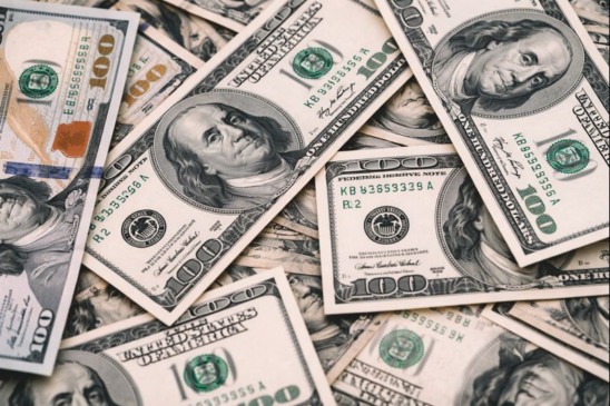 Imagem mostra notas de dólar americano em destaque, representando a variação da moeda no mercado financeiro