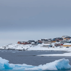 Costa da Groenl&acirc;ndia com icebergs e vilarejo ao fundo em &aacute;rea estrat&eacute;gica do &Aacute;rtico
