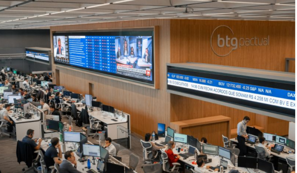 Escritório moderno com o logotipo do BTG Pactual em destaque na parede de madeira.